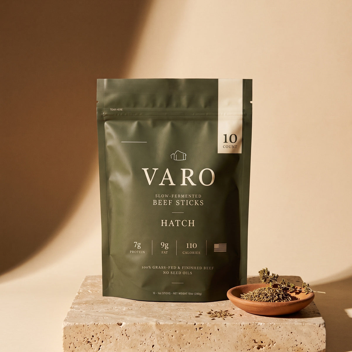 HATCH bag of VARO slow-fermented beef sticks on a travertine block beside a small terracotta dish