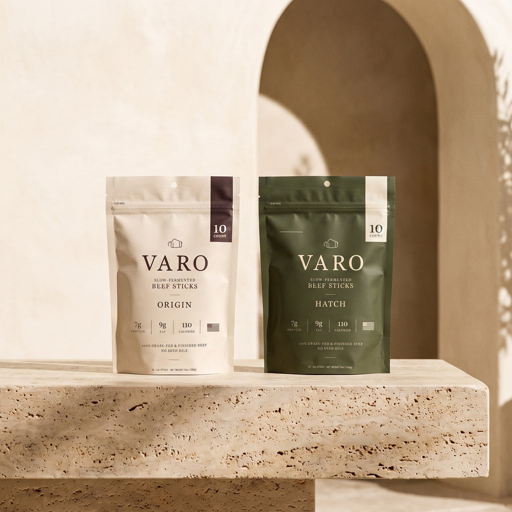ORIGIN and HATCH bags of VARO slow-fermented beef sticks on a sunlit travertine ledge